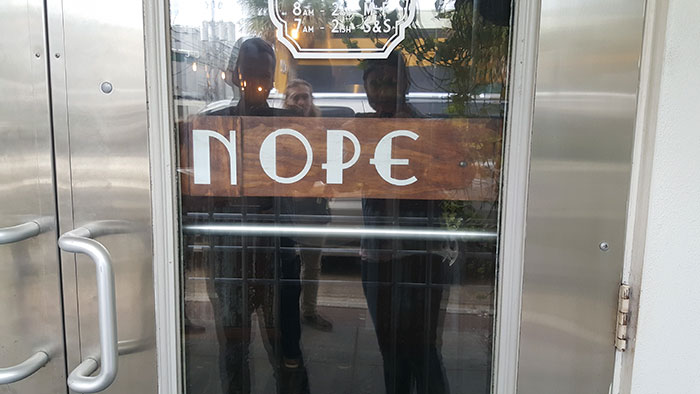 a glass door with wooden board with the word nope