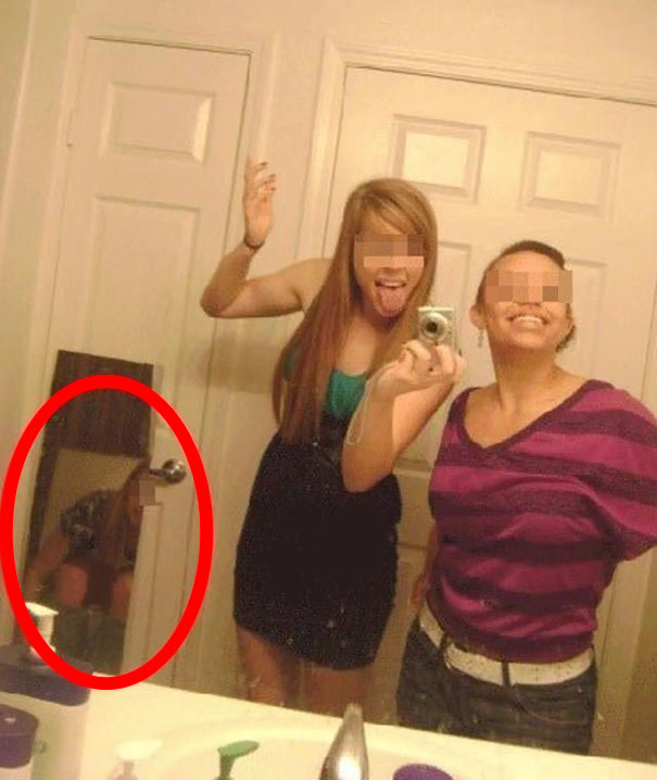Friends making selfie in the mirror with her friend on a toilet in the reflection 