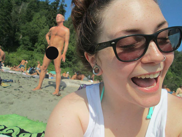 Woman taking a selfie in front of a naked man 