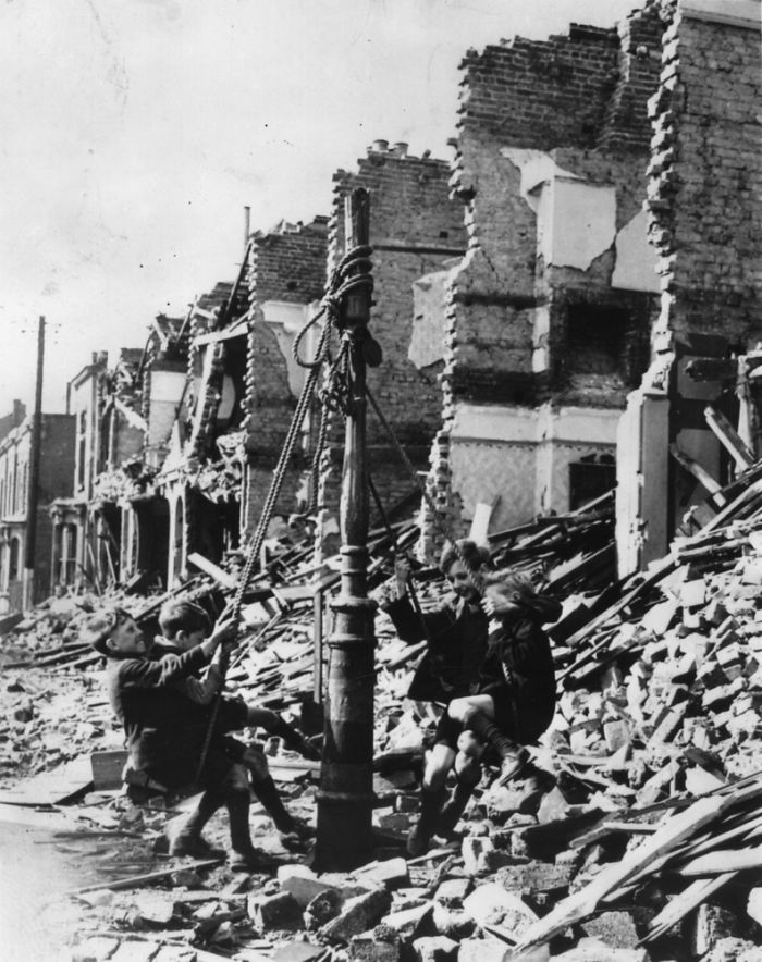 Young Boys Swinging From A Lamp Post In The Midst Of Rubble Left By A Bombing Raid On London During The Blitz, 1940