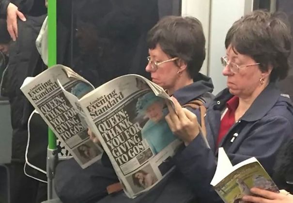 Two womans reading same newspaper and looking similar