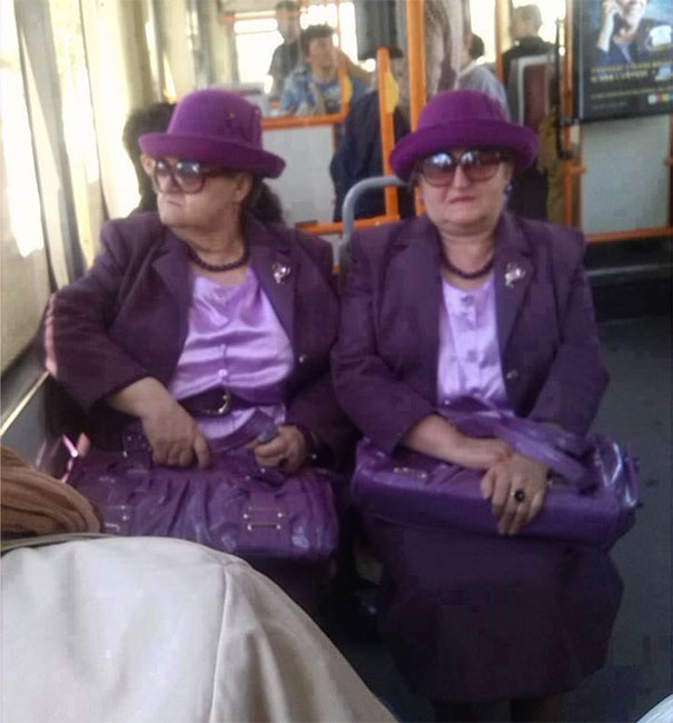 Two womans sitting and wearing same purple clothes