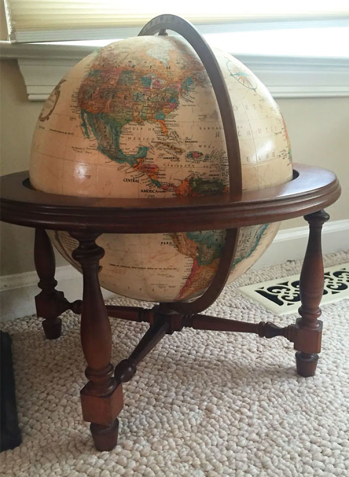 Vintage globe on a wooden stand found in a thrift store, showcasing detailed world map.