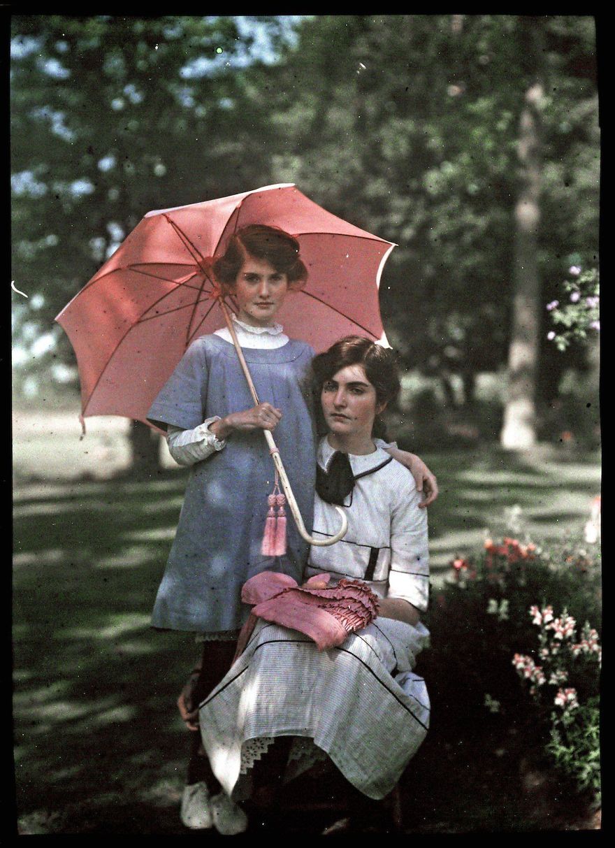 The Younger Girl Stands Beside Her Sister Holding A Pink Parasol. The Older Girl Rests Her Bonnet On Her Lap, 1908