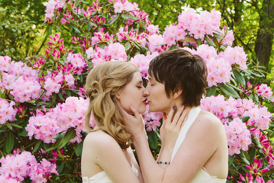 Two women kissing near flowers 