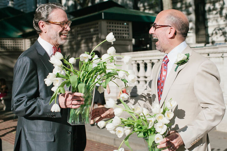 Two happy men holding flowers and laughing 
