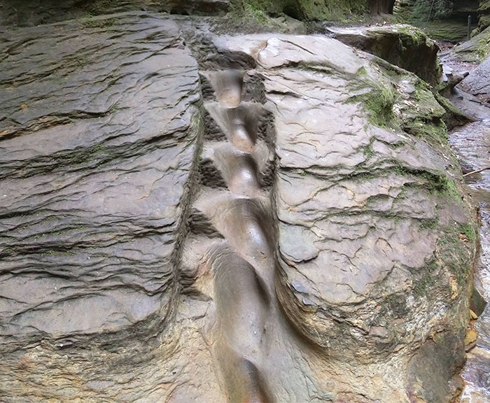 Escalinata desgastada en una pared de piedra sobre un arroyo