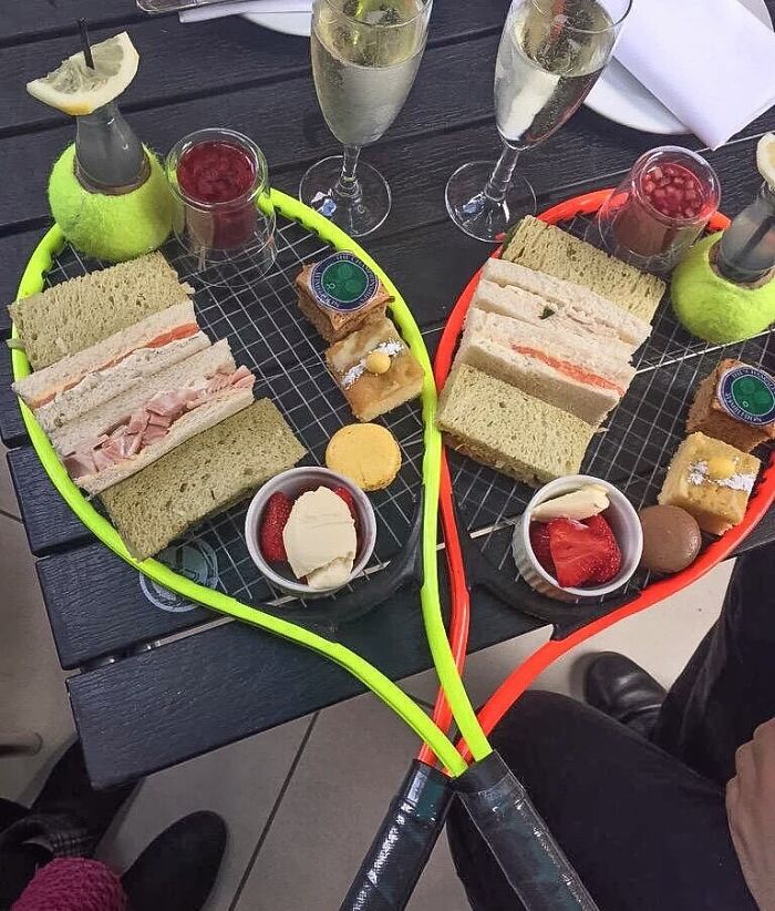 Tennis racquets used as unique food serving platters with sandwiches and desserts.