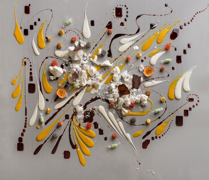 Artistic restaurant dish with colorful sauces and toppings scattered on a table, exemplifying creative food serving.