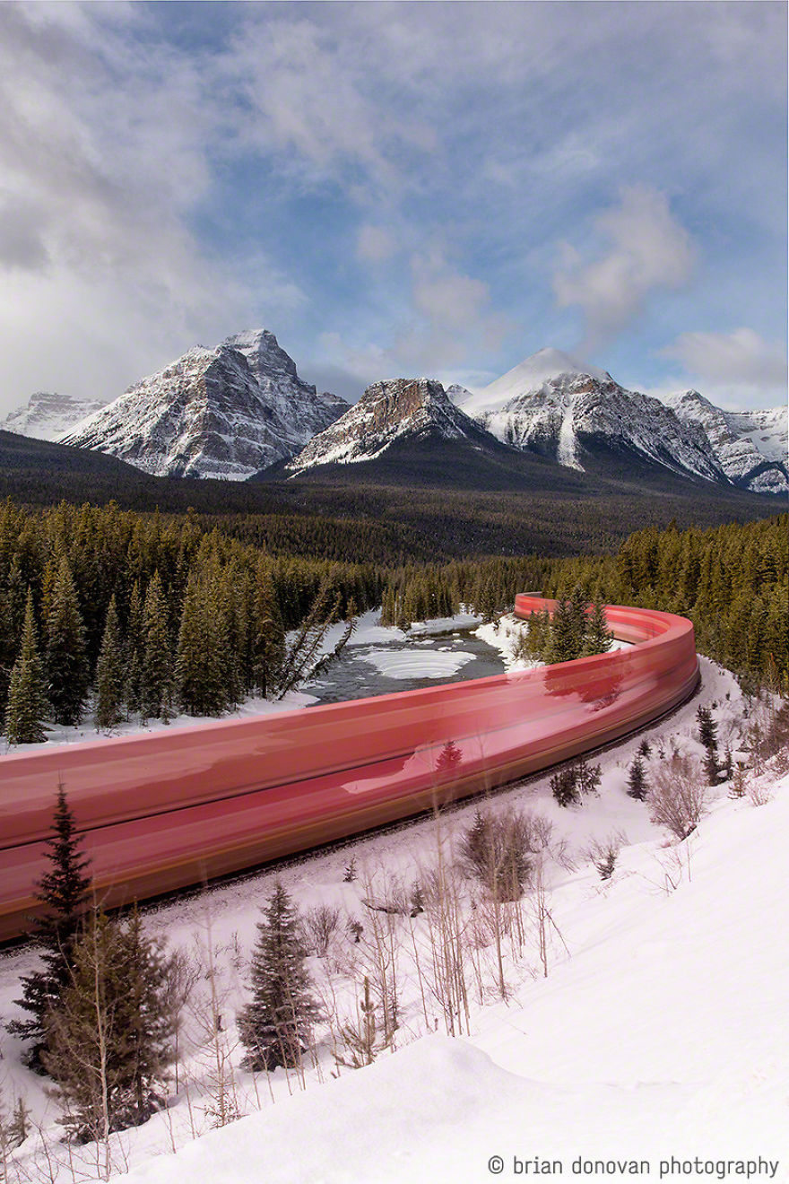 A Long Exposure Photo Of A Train Roaring Through The Canadian Rockies
