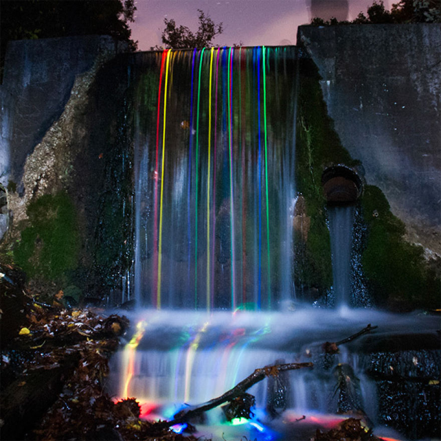 Long Exposure Shot Of Glow Sticks Dropped Into A Waterfall