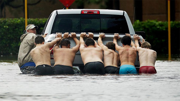 People Push A Stalled Pickup To Through A Flooded Street In Houston