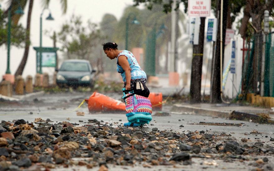 A Woman Pulls A Travel Case On A Rock Scattered Road In The Aftermath Of Hurricane Irma In Fajardo, Puerto Rico