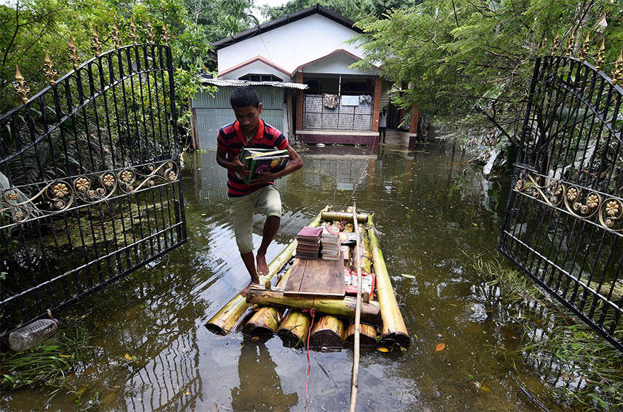 A Boy Uses A Banana Raft To Transport His Books In Jakhalabandha Area In Nagaon District, In The Northeastern State Of Assam, India