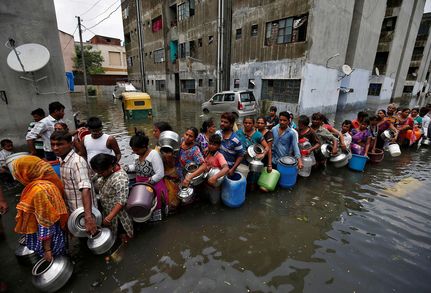 People Wait In A Line To Collect Drinking Water From A Municipal Tanker At A Flooded Residential Colony In Ahmedabad, India