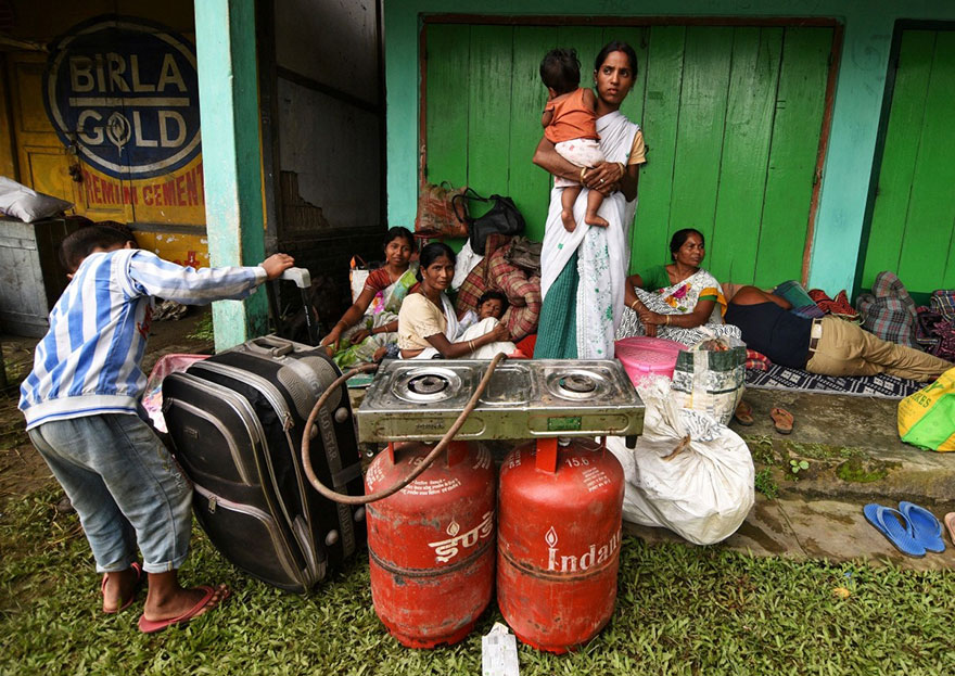 Flood Affected Families Take Shelter In Front Of A Shop And Wait For Relief Material In Jakhalabandha Area In Nagaon District, In The Northeastern State Of Assam, India