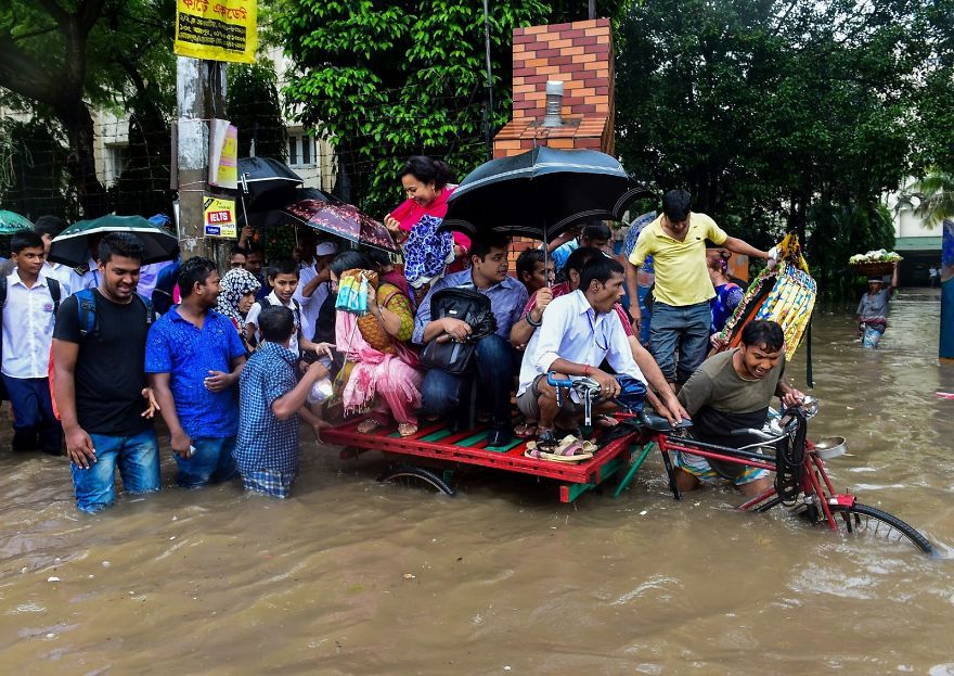 Bangladeshi Commuters Use A Rickshaw To Cross A Flooded Street In Dhaka
