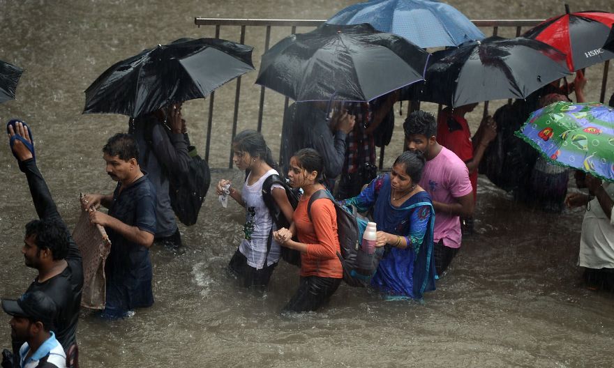 People Walk Along A Flooded Street In Mumbai