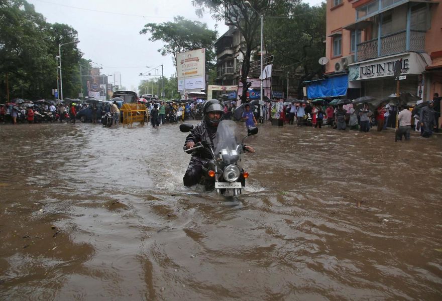 A Man Rides His Motorbike Through A Water-logged Road During Rains In Mumbai