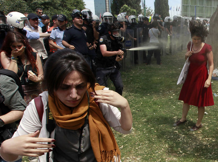 A Turkish Riot Policeman Uses Tear Gas As People Protest Against The Destruction Of Trees In A Park Brought About By A Pedestrian Project, In Taksim Square In Central Istanbul, 28 May 2013