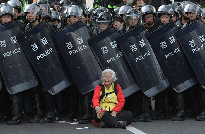 A Woman Sits In Front Of Riot Police Blocking The Road To Protect Protesters During The Anti-Government Protest In Seoul, South Korea, 24 April 2015