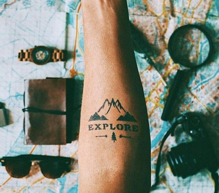 Explore word and mountain arm tattoo