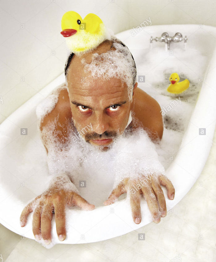 Man in a bubble bathtub with a rubber duck on his head