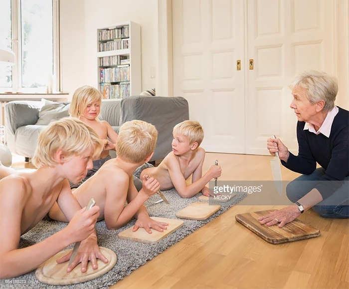 Grandma shows how to play the knife game for four boys in the living room