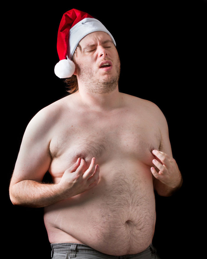A topless fat man with a Santa hat pinches his nipples