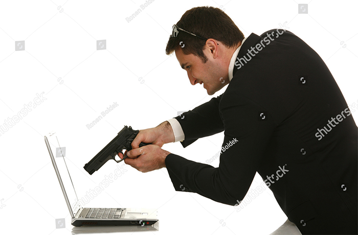 A man in a black suit attempts to shoot the laptop