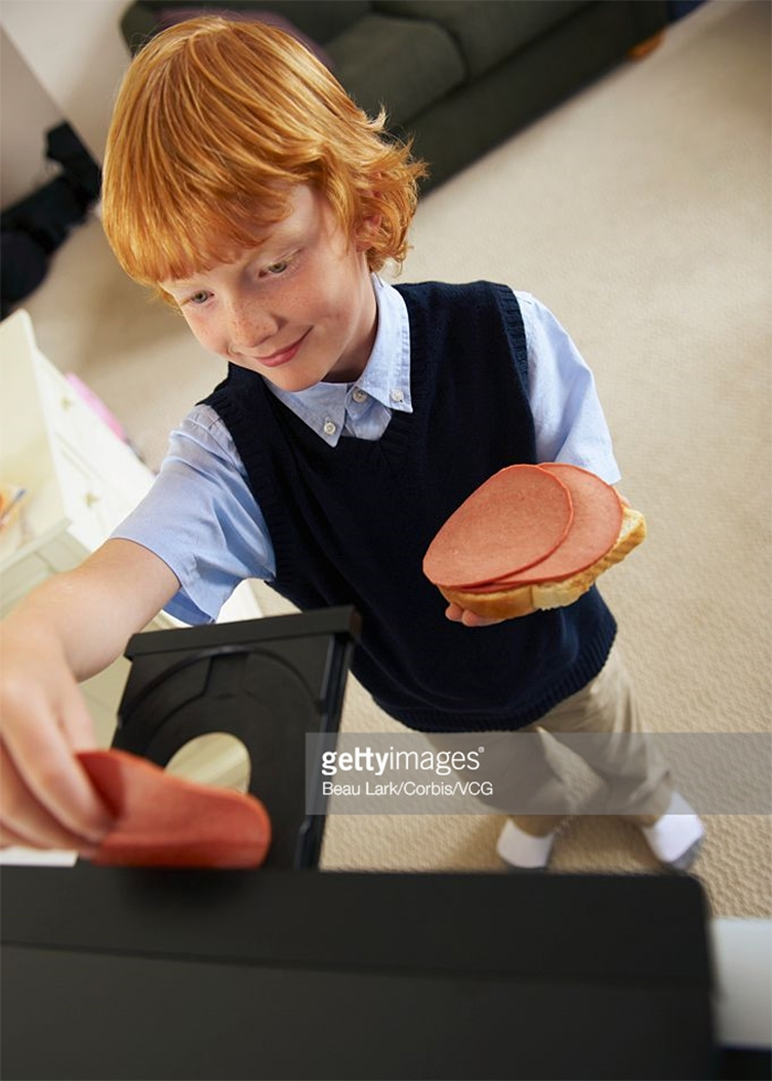 A boy placing large sausage slice in cd player