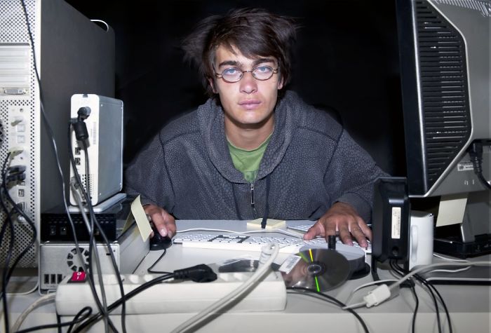 Young man with glasses sitting near computer