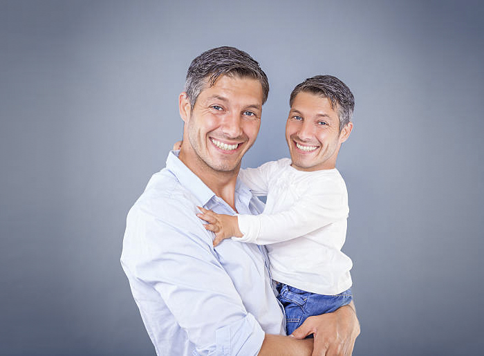 A man holding a kid with the same faces photoshopped