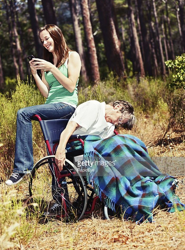 Happy young woman on the phone while older woman falling out of wheelchair