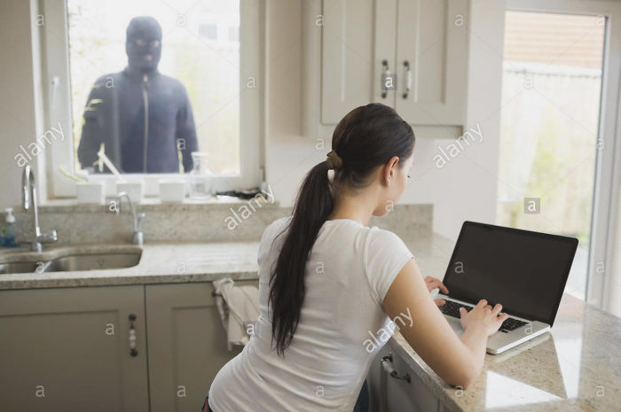 Woman sitting near turned off laptop and working and outside near window stands intruder
