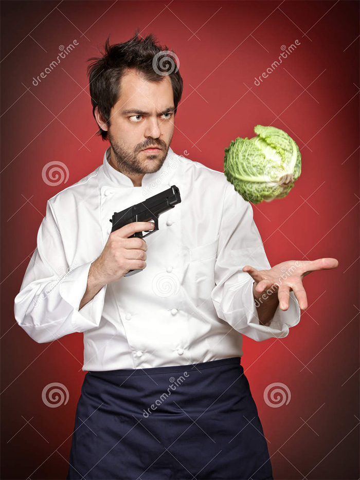 Man cook pointing a gun at savoy cabbage