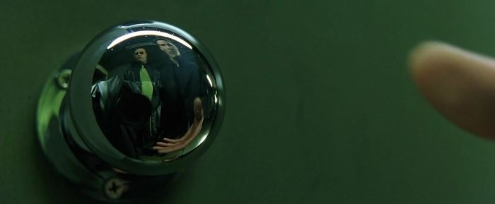 They Couldn't Hide The Camera In The Doorknob's Reflection Of This Scene Of The Matrix, So They Put A Coat Over It And A Half Tie To Match With Morpheus'