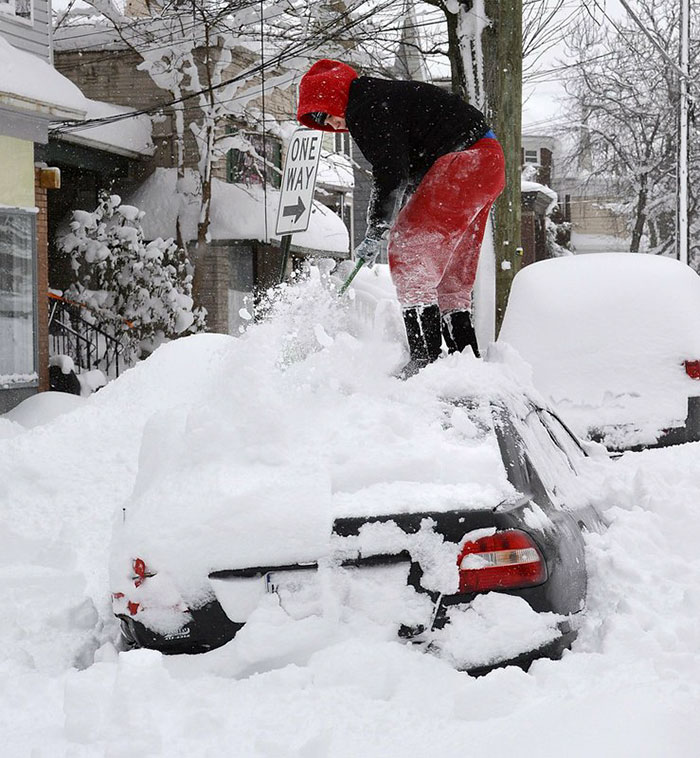 Woman Stands On The Roof Of Her Car As She Brushes Off Snow In Erie, Pa