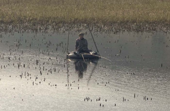 Pescador usando un neumático como barca en un lago camino a Wonsan