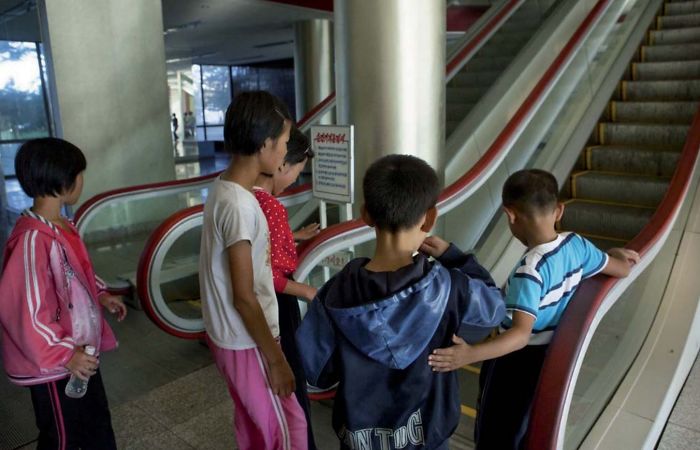 Niños del campo que tienen miedo de las escaleras automáticas porque nunca las habían visto
