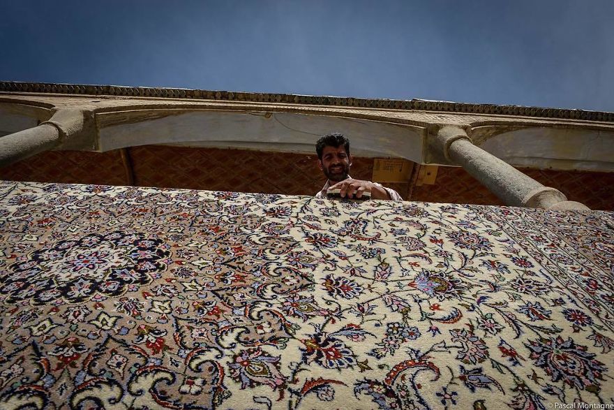 A Man Washes A Carpet In Isfahan Backyard Bazar