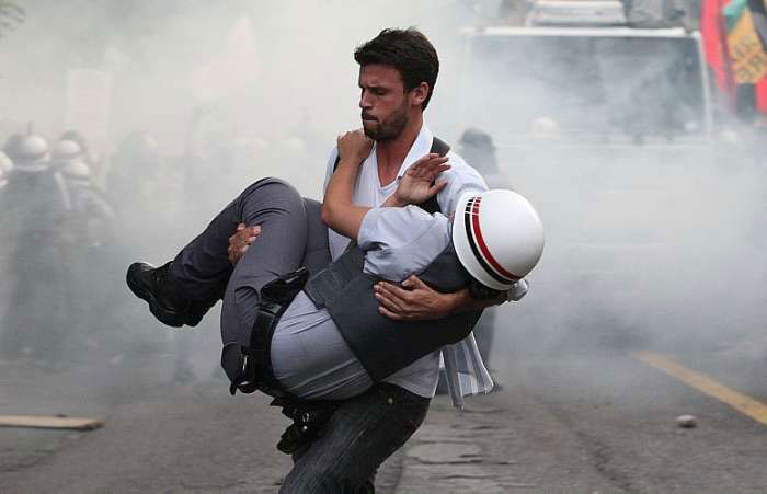 Brazilian Protester Carrying A Cop That Was Hurt During The Riots In Sao Paulo