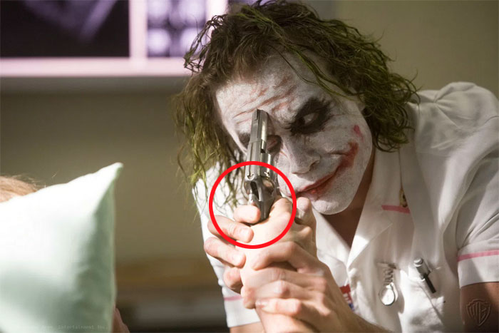 Joker tiene el pulgar puesto en el martillo. Incluso aunque pulsaran el gatillo, no se podría accionar