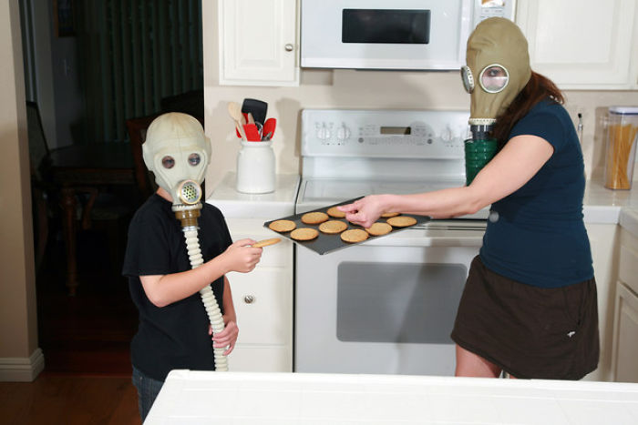 A woman and his son with gas masks trying out baked cookies