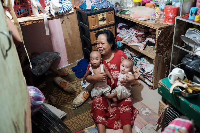 Mujer con sus nietos en su pequeña habitación. 5 personas viven en esta pequeña habitación