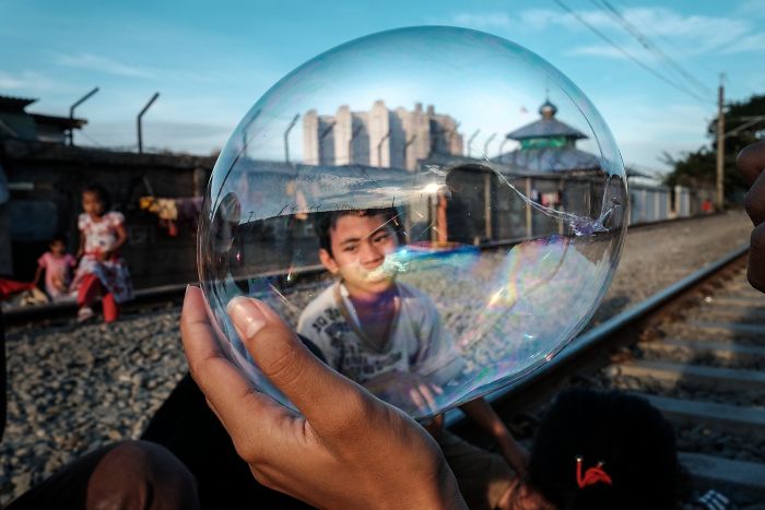 Unos niños juegan con un globo mientras están sentados en las vías activas del tren en una zona de barrios marginales junto a la estación de tren de Yakarta Kota