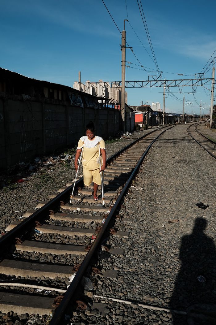 Una mujer con una pierna camina por las vías del tren activas en una zona de barrios marginales junto a la estación de tren de Yakarta Kota