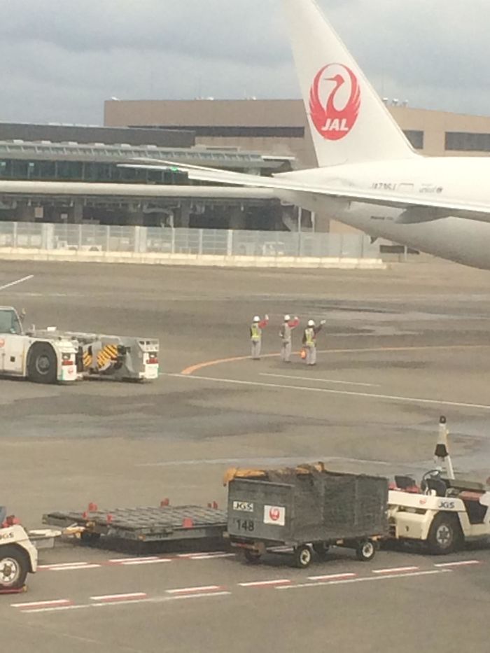El personal de tierra japonés despide al avión que se va
