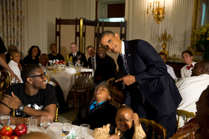 Obama posando para una foto con un chico que se ha quedado dormido en un evento social
