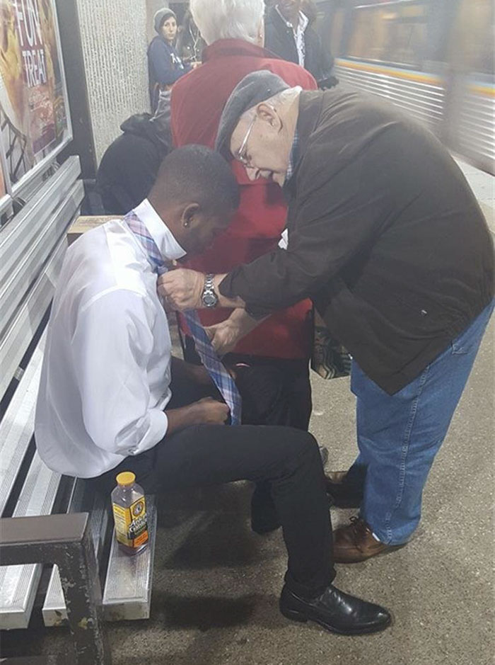 Anciano ayudando a un desconocido a atarse la corbata en el metro